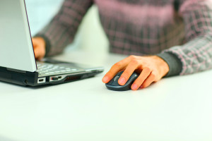 Close-up of male hands on mouse and keyboard of laptop during typing