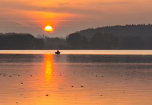 Beautiful lake sunrise with sky reflections in water. Tranquil colorful scene of typical polish lake in Mazury lake district.