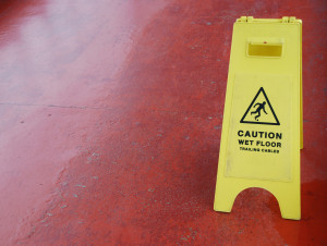 yellow caution sign regarding slippery surface (red pavement background)